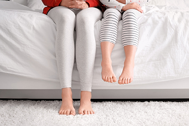 Woman and little child sitting on bed, closeup